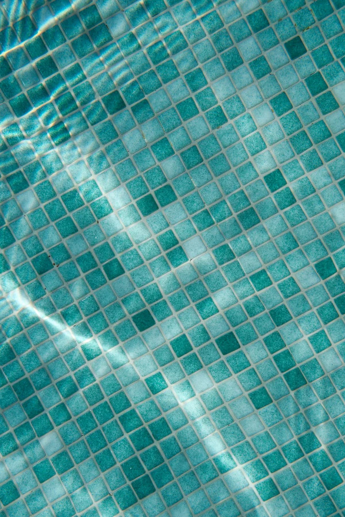 Close view of small blue-green swimming pool tiles