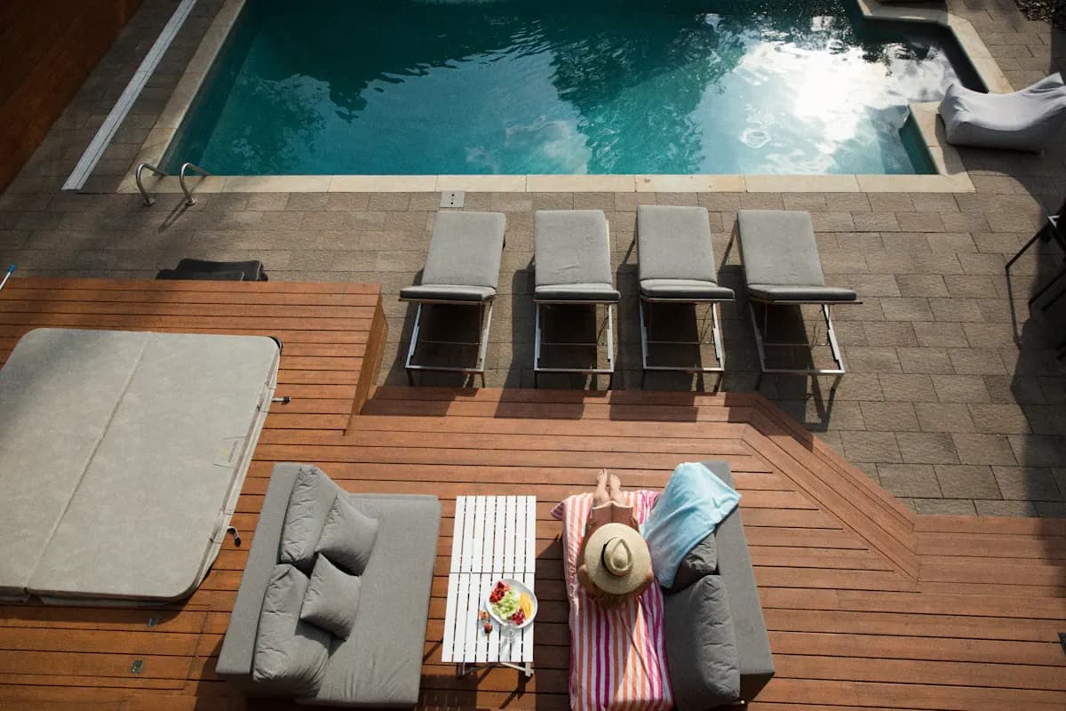 Overhead view of a pool, covered hot tub, loungers and timber deck seating