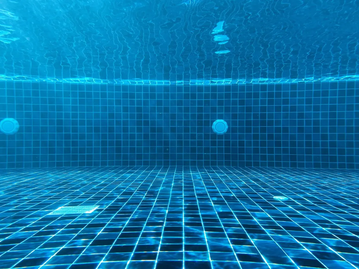 Underwater view of blue pool tiles and wall fittings